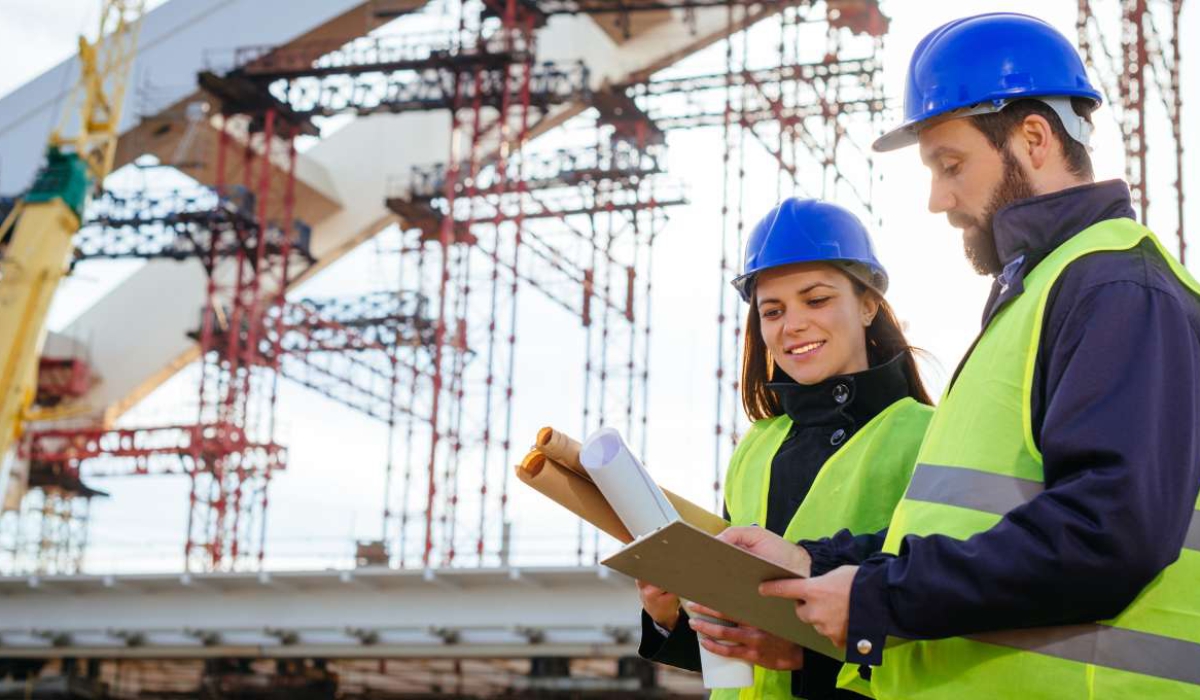 Teamwork-in-construction-industry---two-engineers-working-together-on-construction-site-with-blueprints-and-plans-645373486